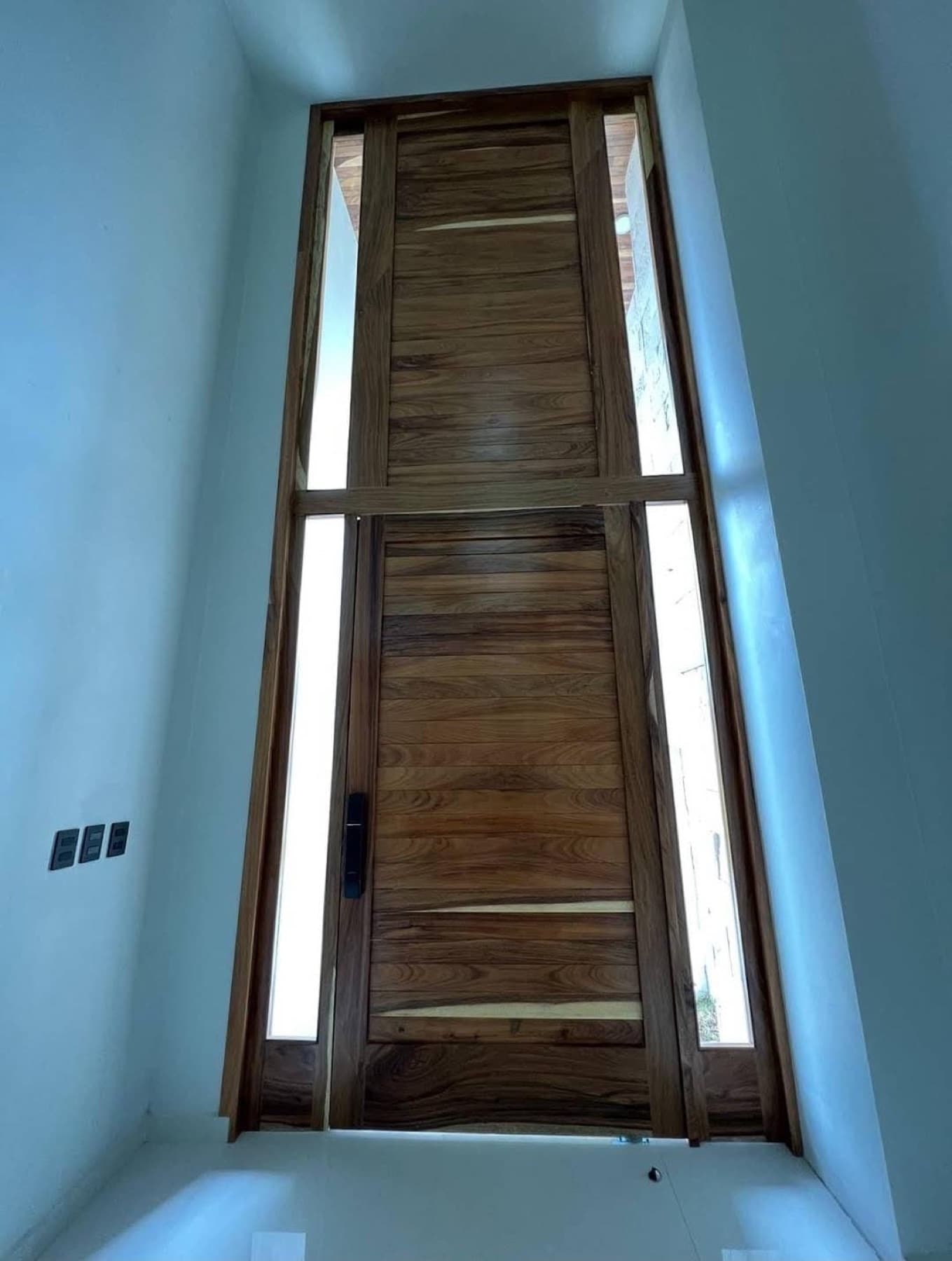 Puerta principal de madera a doble altura instalada